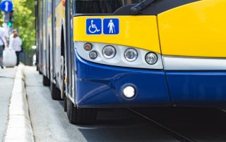 Photo de l'avant d'un autobus sur lequel sont apposés les logos d'une personne en fauteuil roulant et d'une personne avec une canne.